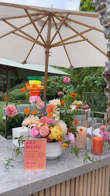 a table with flowers and candles under an umbrella