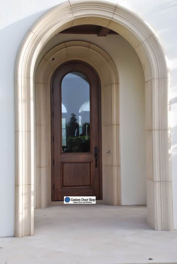 an arched wooden door in front of a white building