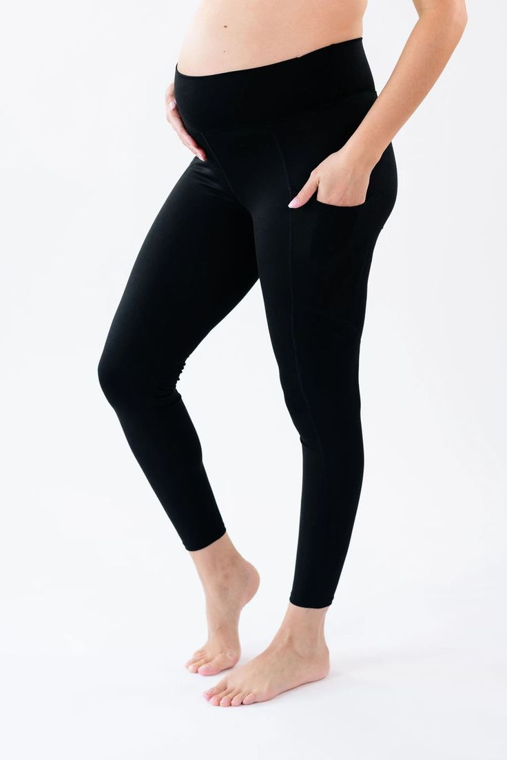 a pregnant woman wearing black leggings and holding her belly up to the side