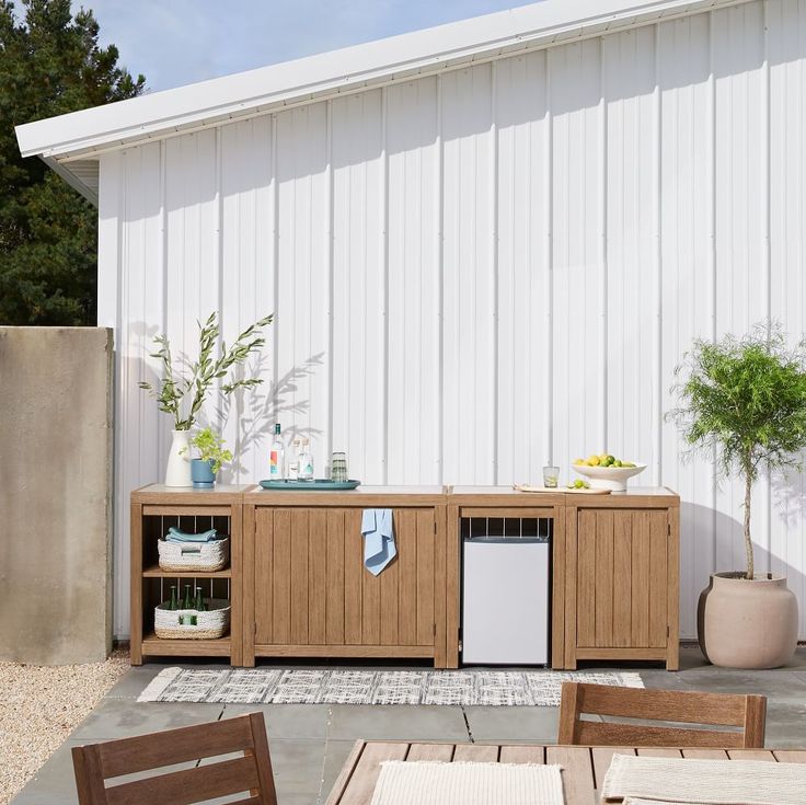 an outdoor patio with table and chairs next to a white barn door, potted plants on the side