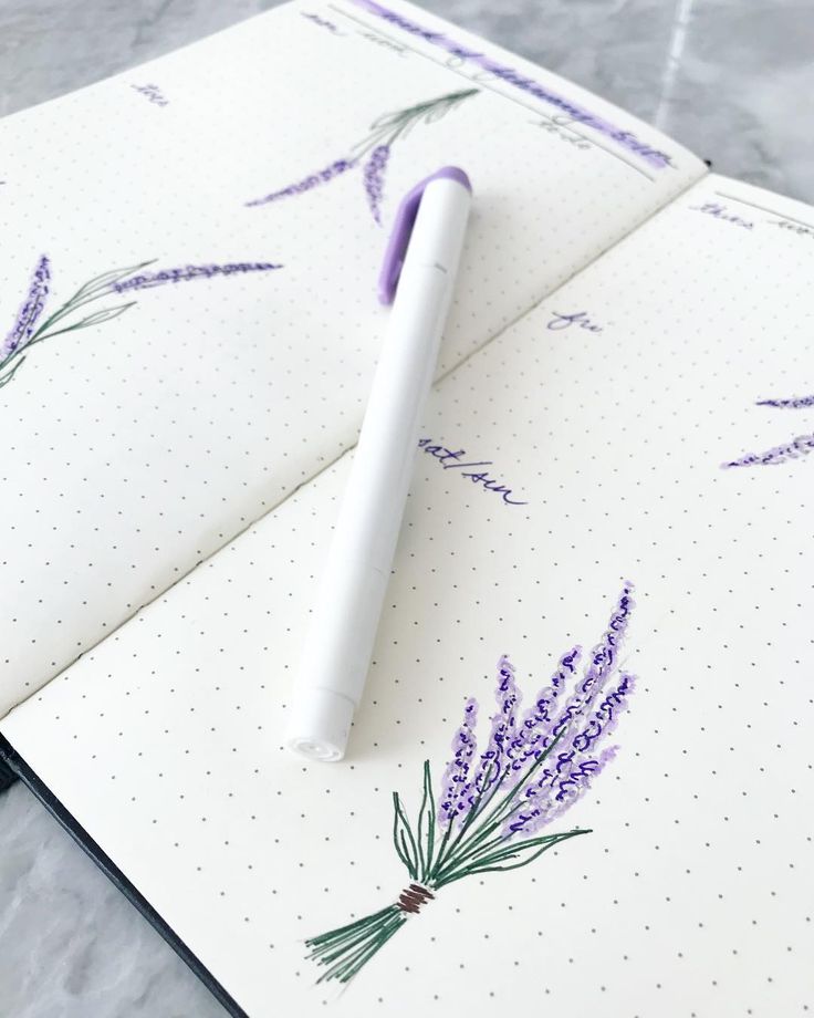 an open notebook with purple flowers on it and a pen resting on the top cover