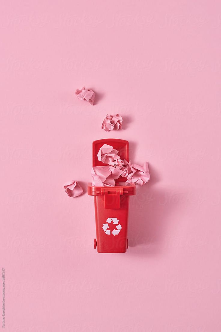 a red trash can filled with crumpled paper