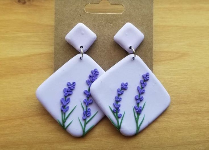 a pair of earrings with lavender flowers painted on them