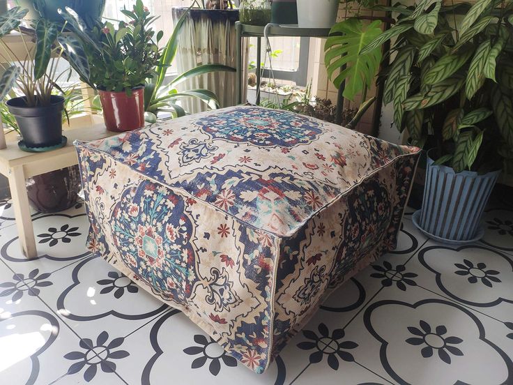 an ottoman sitting on top of a tiled floor next to potted plants