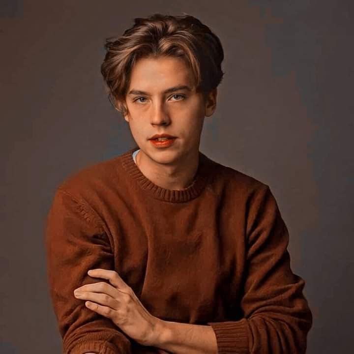 a young man with his arms crossed posing for a photo in front of a gray background