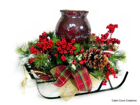 a red vase sitting on top of a sled filled with pine cones and berries