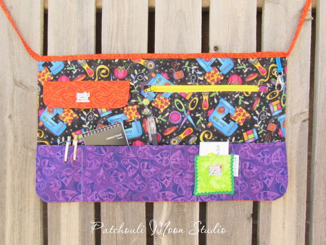 a purple and orange purse sitting on top of a wooden fence