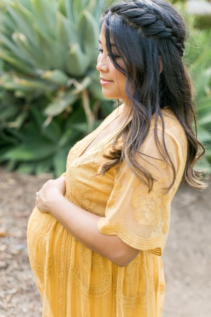 a pregnant woman in a yellow dress poses for the camera