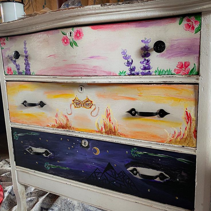 an old dresser has been painted with flowers and other designs on it's drawers