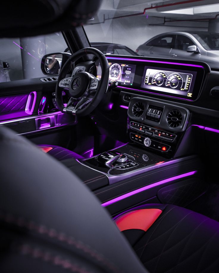 the interior of a car with purple lights and black leather seats, including steering wheel controls