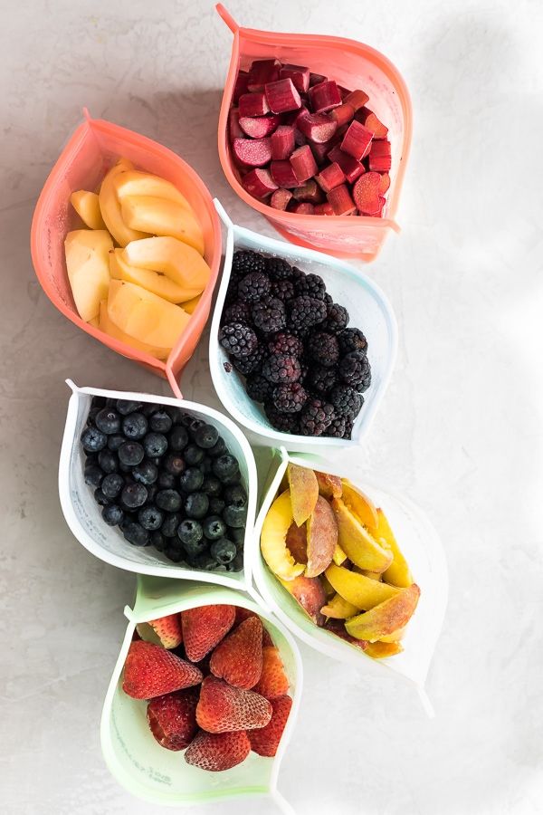 four bowls filled with different types of fruit on top of a white countertop next to each other