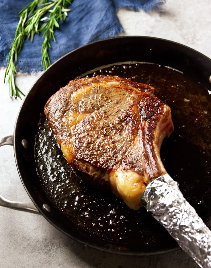 a piece of meat is being cooked in a skillet with a knife on the side