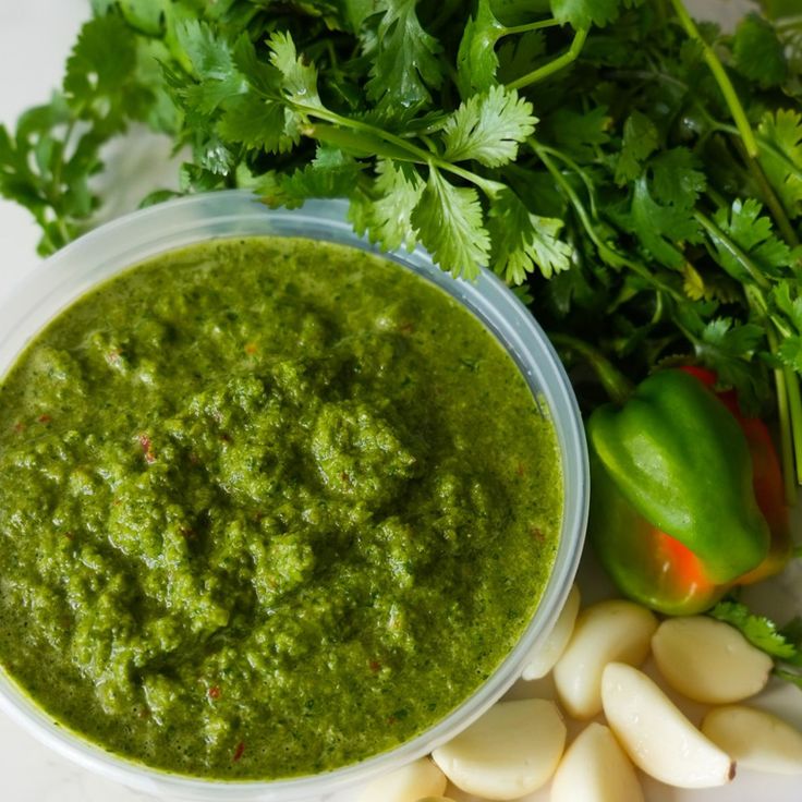 a bowl filled with green sauce next to some vegetables