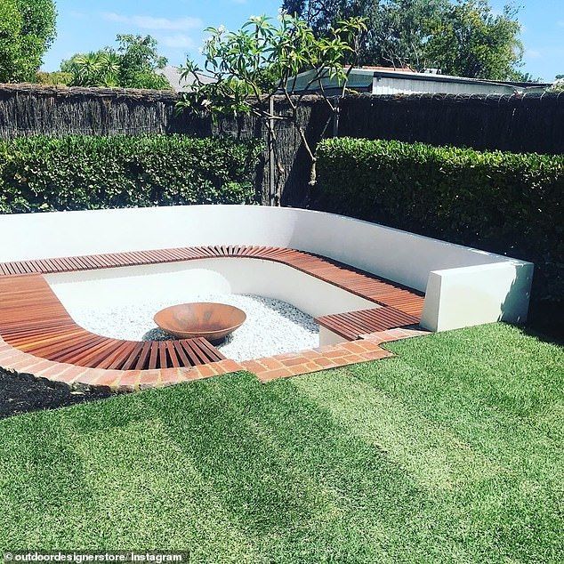 a wooden bench sitting in the middle of a lush green yard next to a hedge