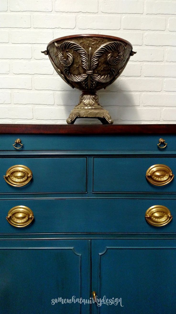 an ornate metal bowl on top of a blue dresser