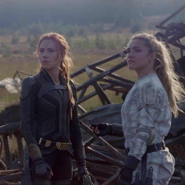 two women standing next to each other in front of a pile of junk