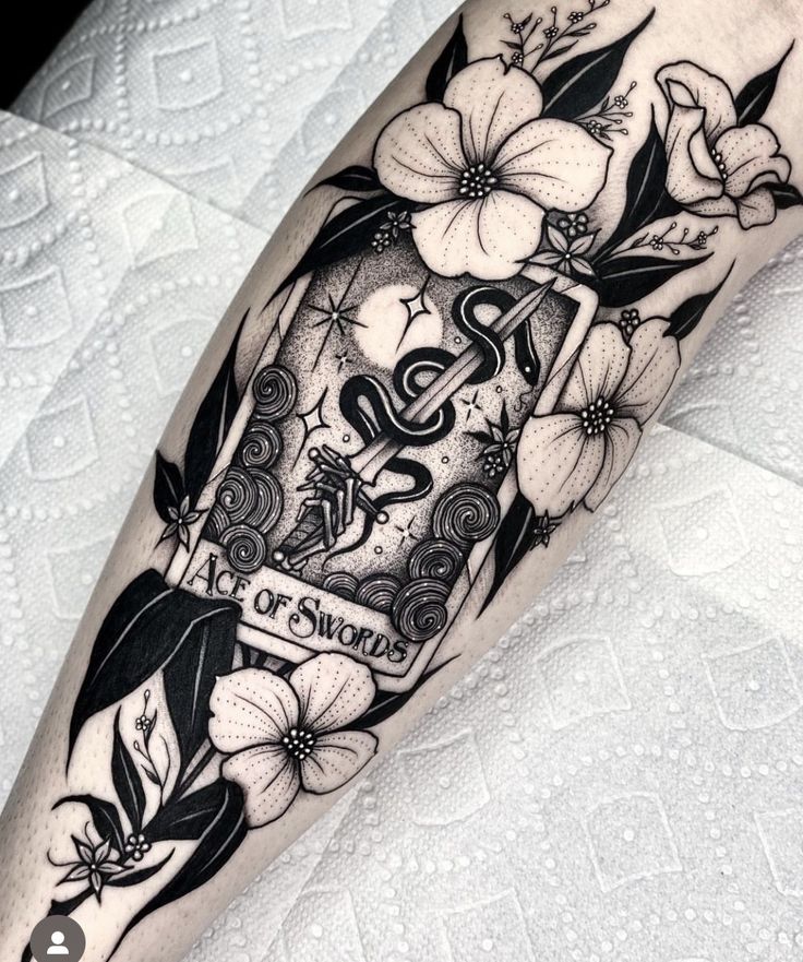 a black and white tattoo with flowers on the leg that says out of snow written in it