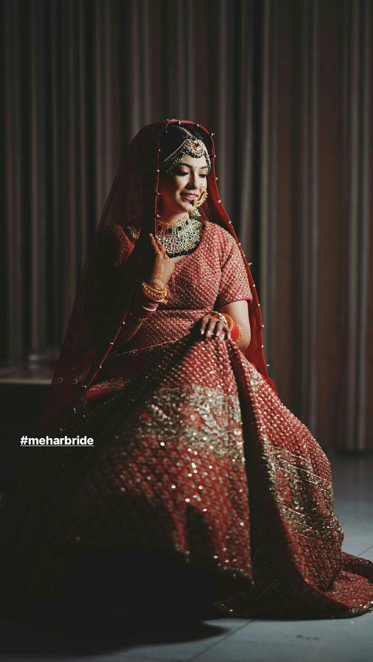 a woman in a red and gold dress sitting on the floor with her hand up to her face