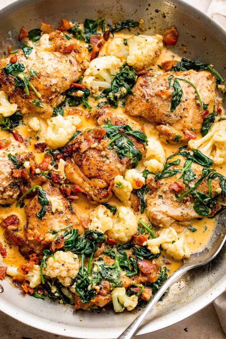 a skillet filled with chicken, cauliflower and spinach