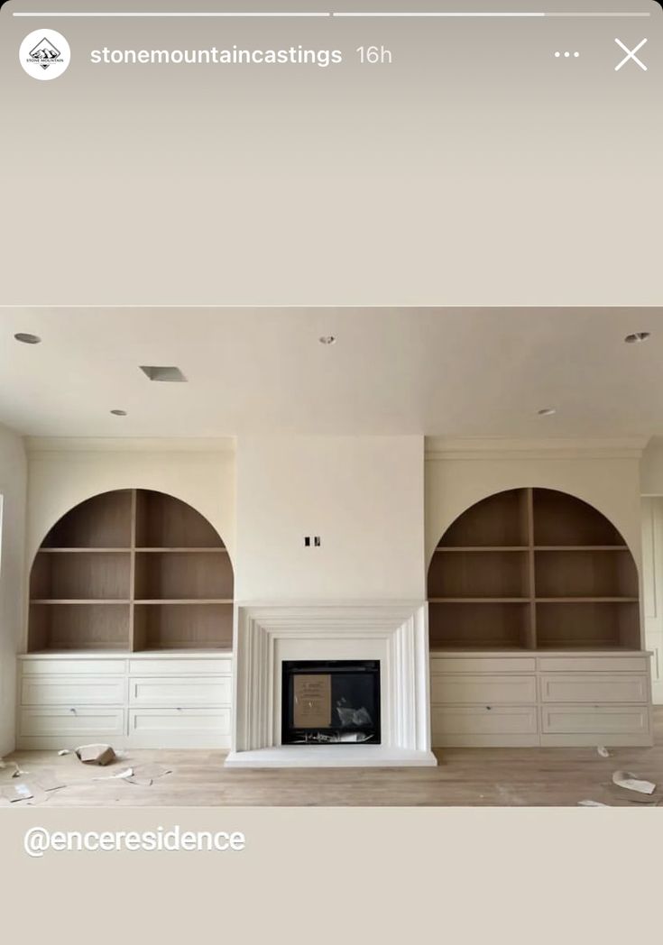 an empty living room with built in bookshelves and cabinets on either side of the fireplace