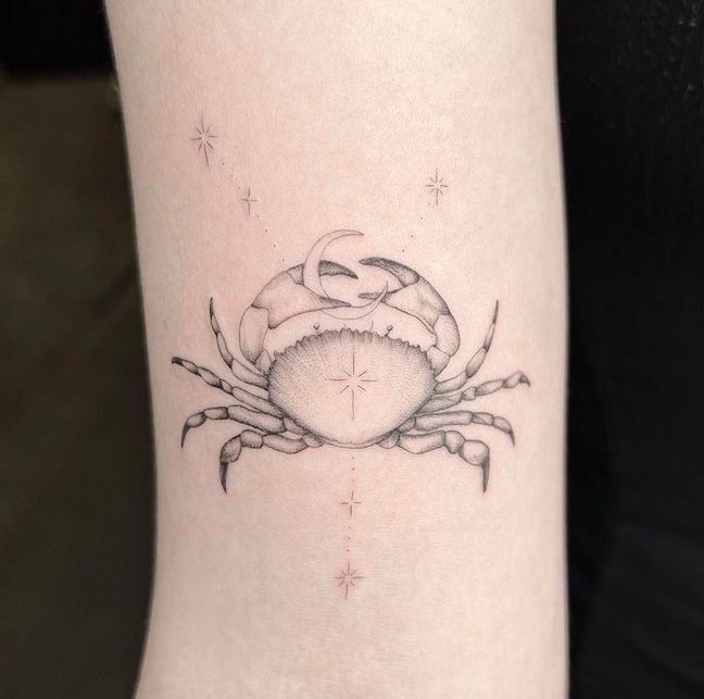 a small crab tattoo on the right arm and leg, with stars in the background