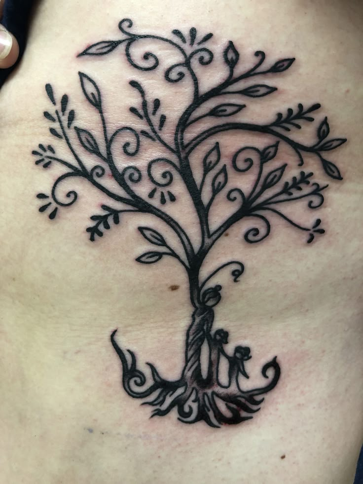 a woman's stomach with an intricate tree tattoo on the side of her belly