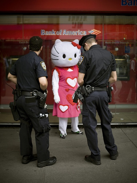 two police officers standing in front of a hello kitty store with a woman dressed as a cat