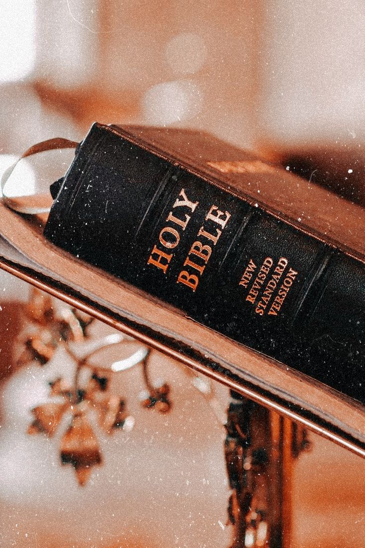 an old book sitting on top of a glass table next to a chandelier