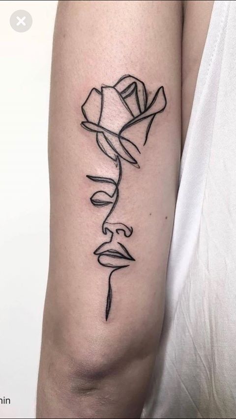 a black and white photo of a woman's arm with a rose tattoo on it