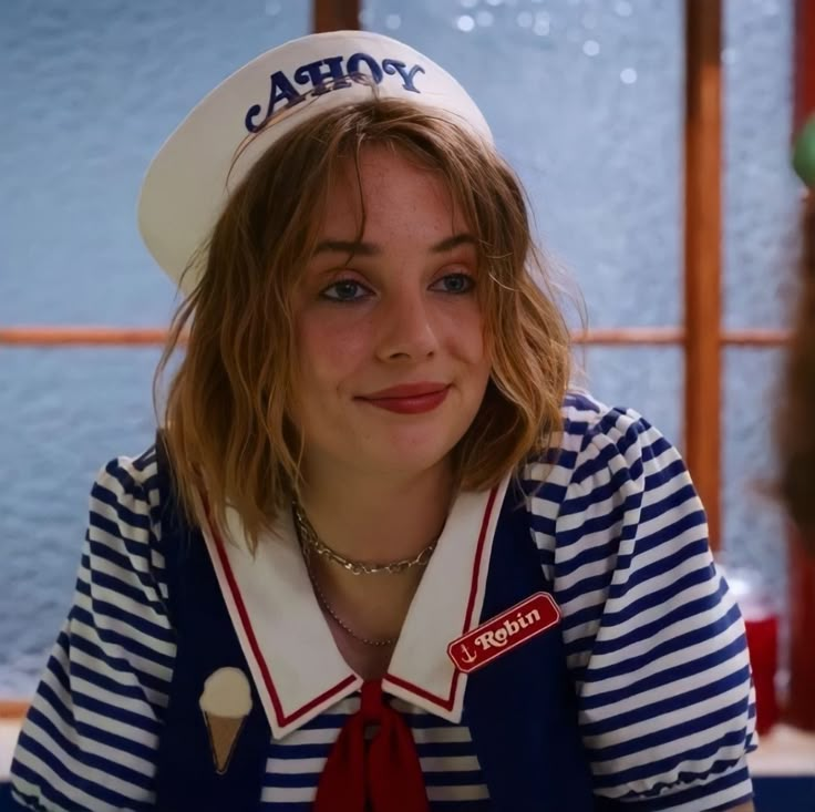 a woman wearing a sailor's hat and striped shirt is looking at the camera