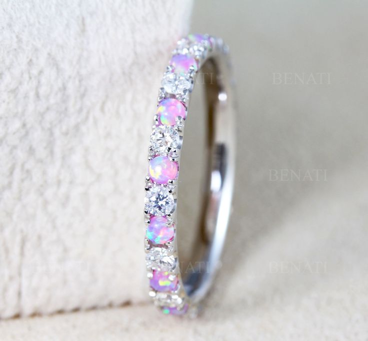 a white gold ring with pink and white opal inlays sits on a towel