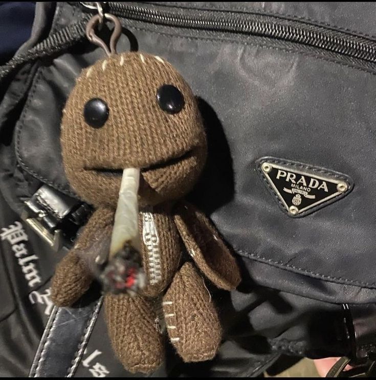 a brown stuffed animal sitting on top of a black bag