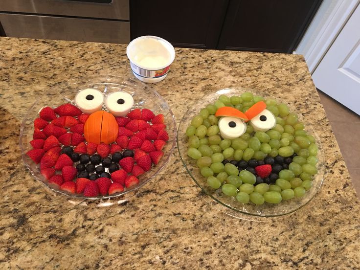 two plates filled with grapes and strawberries in the shape of an angry bird face