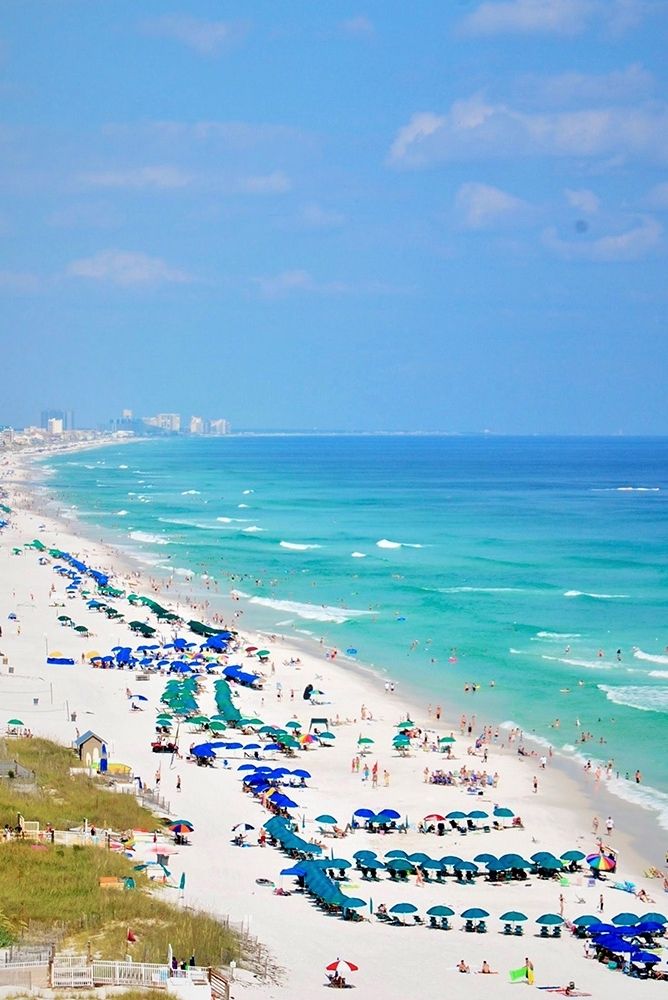 the beach is crowded with people and umbrellas on a sunny day at the ocean