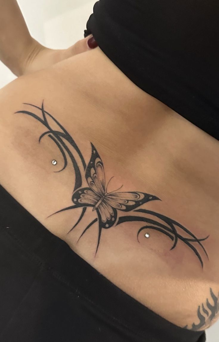 a woman's stomach with a butterfly tattoo on her side and the bottom part of her belly