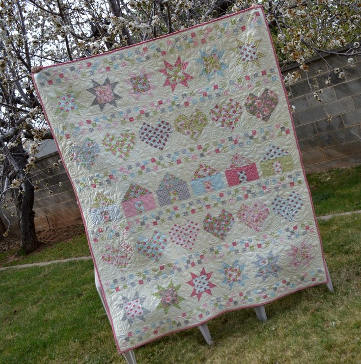 a large quilt is hanging on a clothes line in the grass near a tree and fence