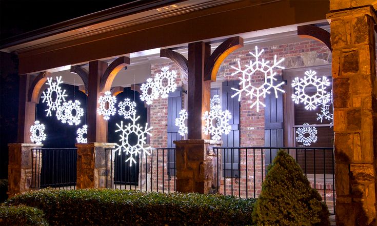 lighted snowflakes are on display in the windows of a brick building at night