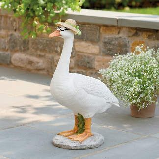 a white goose with a hat and glasses on it's head standing next to a potted plant