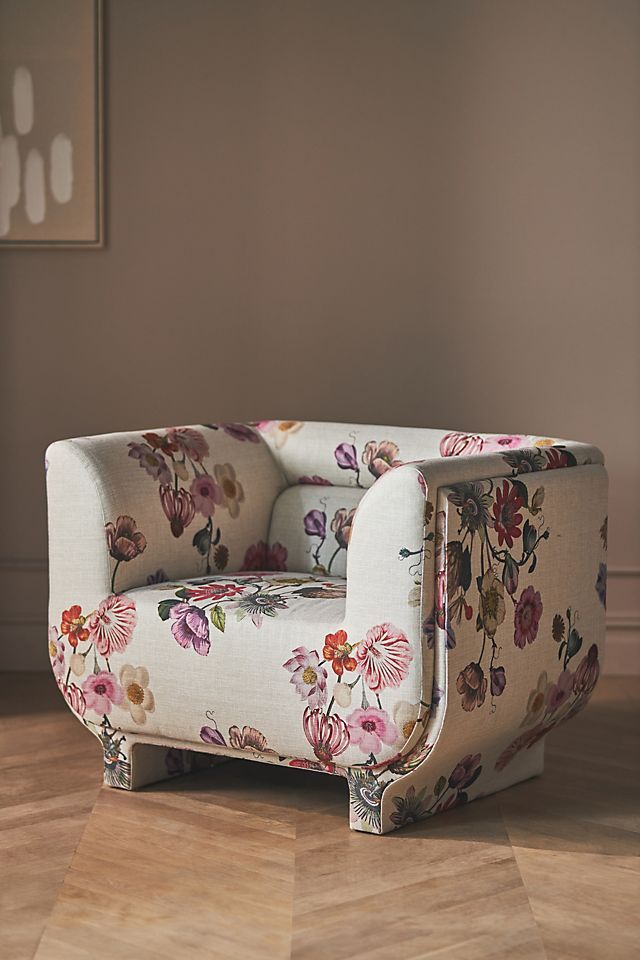 a flowered chair sitting on top of a hard wood floor next to a wall