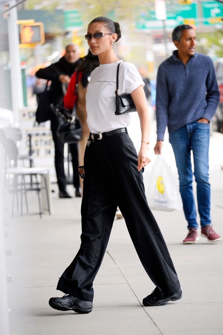 a woman walking down the street wearing black pants