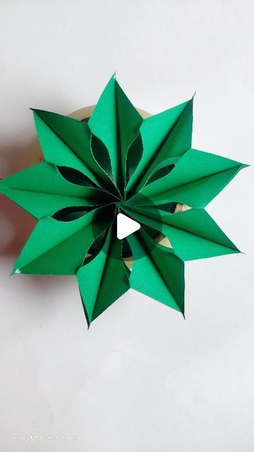 a green origami flower on a white surface