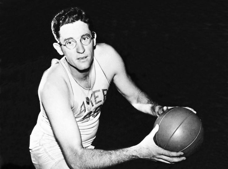 a man holding a basketball in his right hand and wearing glasses on top of it