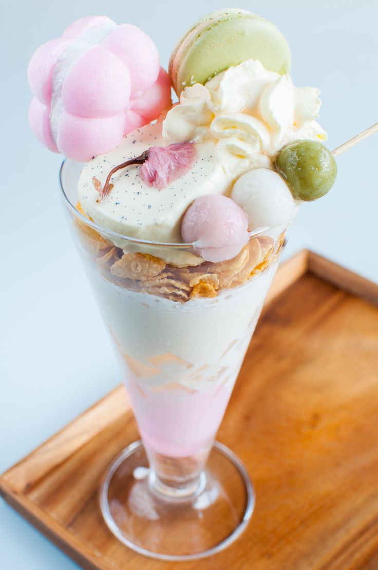 an ice cream sundae with marshmallows and other toppings on a wooden tray