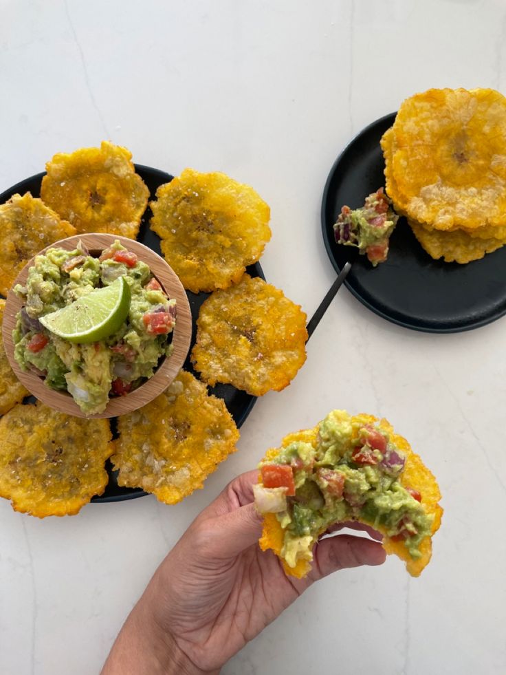 a person is holding up some food on a plate with other foods in the background