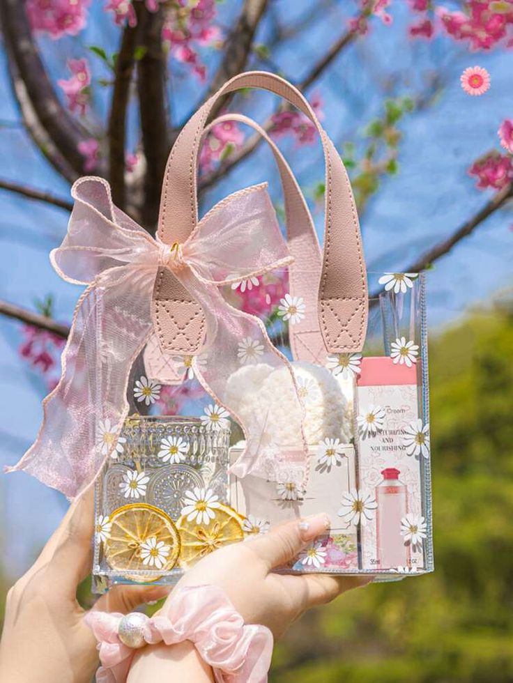 a person holding up a clear bag with flowers and other items in it that are attached to a tree