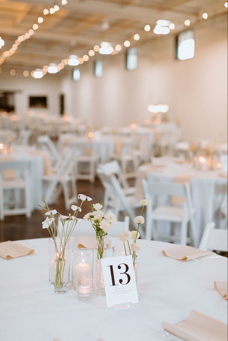 the tables are set up with white linens and centerpieces for an elegant reception