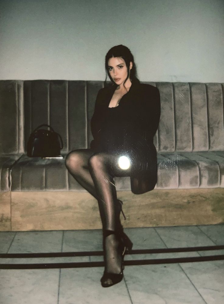 a woman sitting on top of a couch wearing tights and heels with her legs crossed