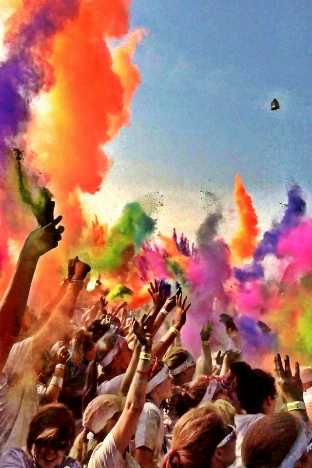 many people are throwing colored powder on each other at the same time as they celebrate