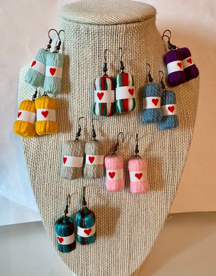 an assortment of colorful crochet earrings hanging from a mannequin's neck