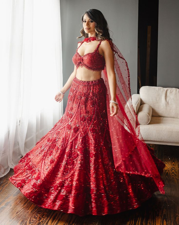 a woman in a red dress standing by a window